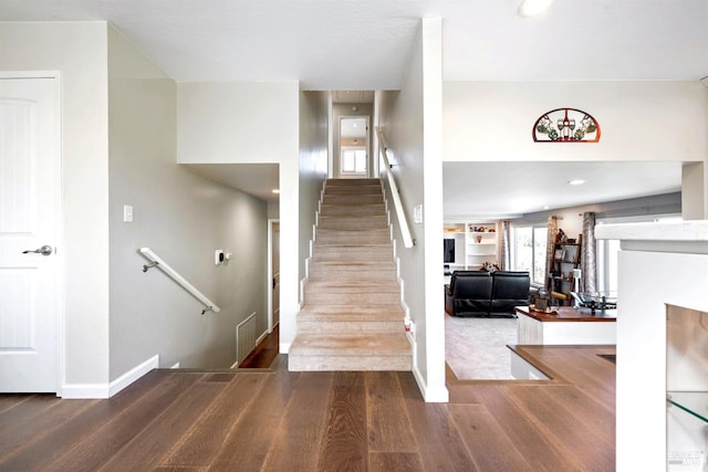 stairs with visible vents, built in shelves, baseboards, and wood finished floors