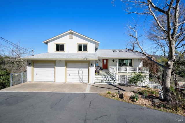 split level home with driveway, an attached garage, a gate, fence, and a porch