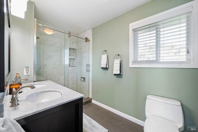 bathroom with double vanity, a stall shower, a sink, and toilet