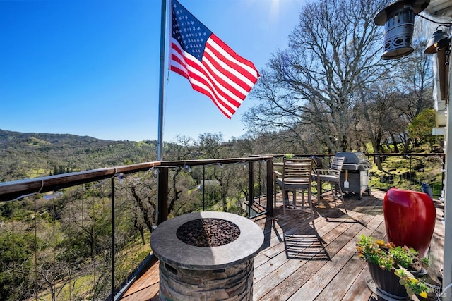 wooden deck with a fire pit and area for grilling