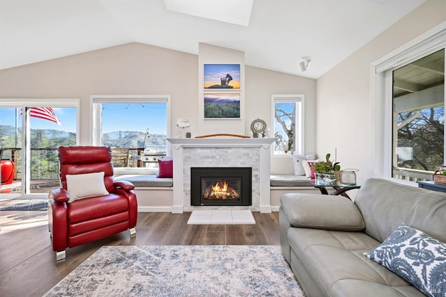 living area with lofted ceiling with skylight, a fireplace, and wood finished floors