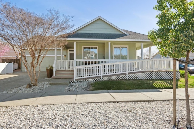 farmhouse inspired home with a porch, concrete driveway, roof with shingles, and a garage