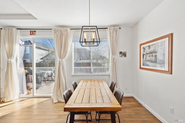 dining space featuring a chandelier, wood finished floors, and baseboards