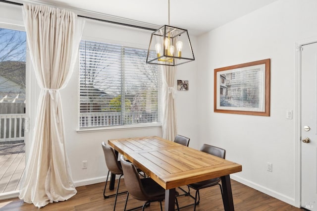 dining space with a notable chandelier, wood finished floors, and baseboards