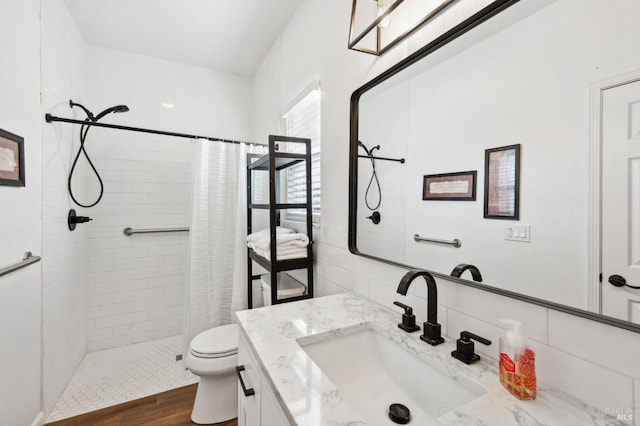 full bath with toilet, a tile shower, and vanity