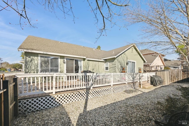 back of property with roof with shingles, fence, and a wooden deck