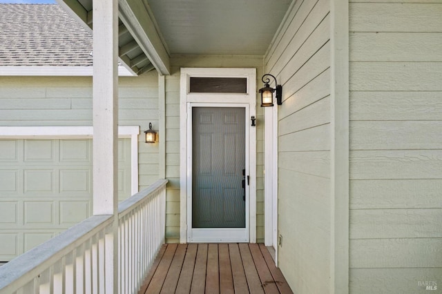 property entrance featuring a garage and roof with shingles