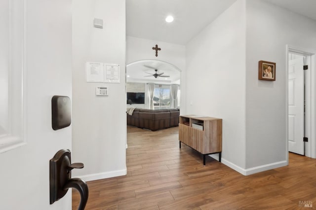 hall with baseboards, arched walkways, wood finished floors, and recessed lighting