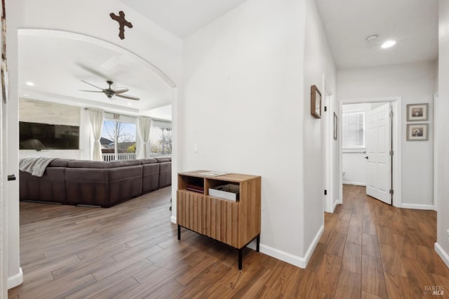 corridor with baseboards, wood finished floors, and recessed lighting