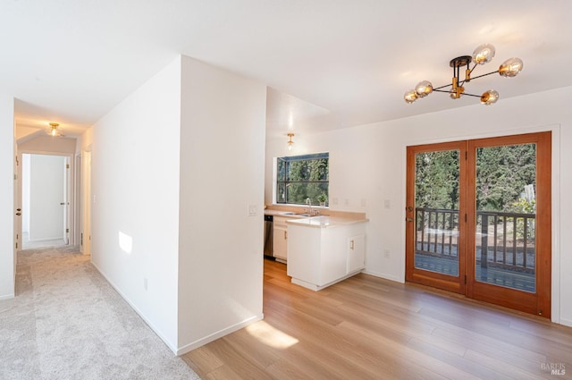 interior space featuring a sink, light wood-style flooring, baseboards, and a notable chandelier