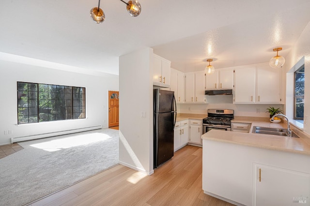 kitchen featuring freestanding refrigerator, stainless steel gas range, light countertops, a baseboard heating unit, and a sink