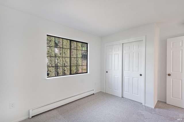 unfurnished bedroom with a closet, light colored carpet, baseboards, and baseboard heating