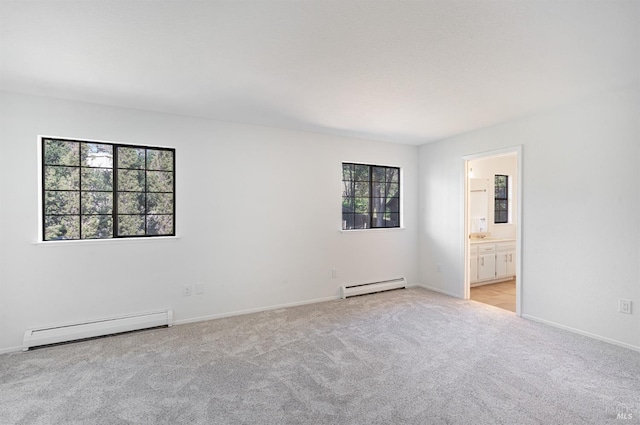 spare room featuring a baseboard radiator, light colored carpet, and baseboards