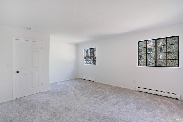 carpeted spare room with a baseboard radiator and baseboards