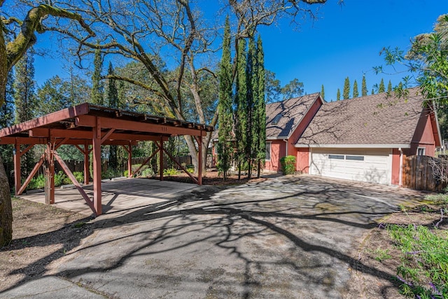 view of front of house featuring a garage, driveway, roof with shingles, and fence