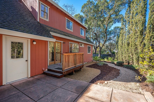 rear view of house with a patio, roof with shingles, fence, and a wooden deck