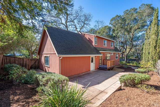 exterior space with a shingled roof, a patio area, and fence