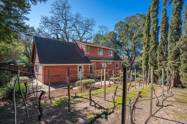 rear view of property with a shingled roof and fence