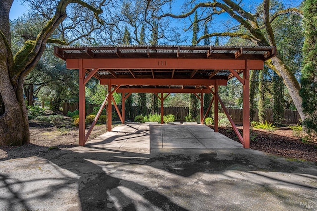 view of patio / terrace featuring a carport, concrete driveway, and a fenced backyard