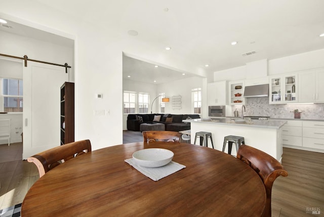 dining room with recessed lighting, a barn door, visible vents, and wood finished floors