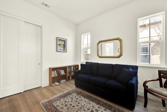 living area with visible vents, baseboards, and wood finished floors