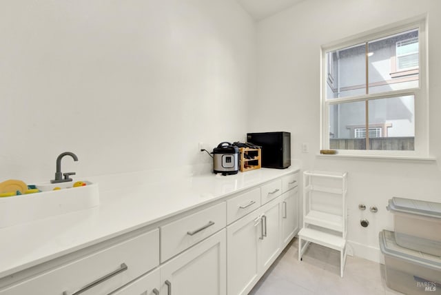 kitchen with light countertops, white cabinets, light tile patterned floors, and baseboards