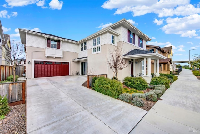 view of front of property with an attached garage, fence, driveway, and stucco siding