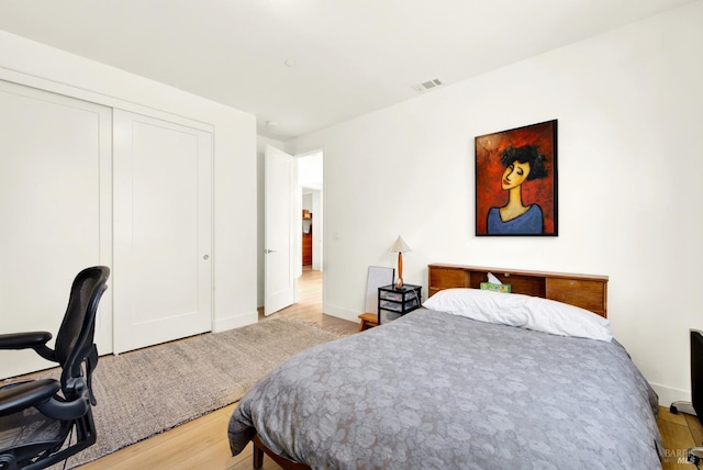 bedroom featuring light wood-style flooring, baseboards, visible vents, and a closet