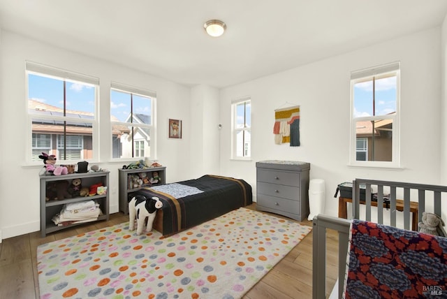 bedroom with hardwood / wood-style flooring, multiple windows, and baseboards