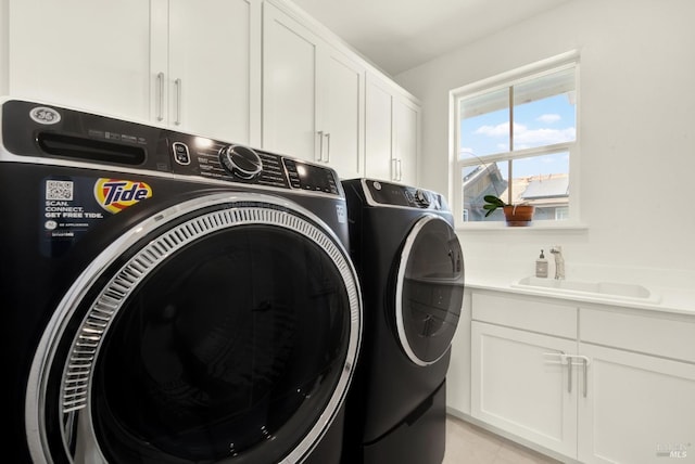 washroom featuring cabinet space, washing machine and dryer, light tile patterned flooring, and a sink