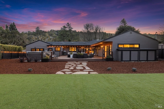 back of house at dusk featuring a wooden deck, an outdoor living space, and a yard