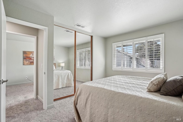 bedroom with carpet floors, a closet, visible vents, and a textured ceiling