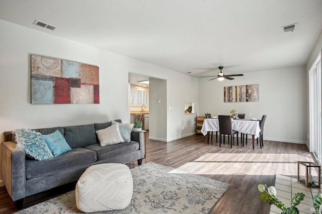 living room with visible vents, ceiling fan, baseboards, and wood finished floors