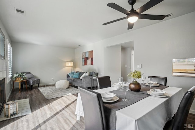 dining room with baseboards, a fireplace, visible vents, and wood finished floors