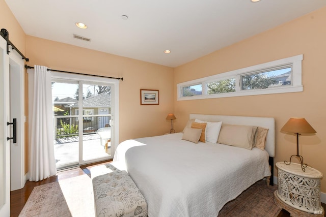 bedroom with a barn door, recessed lighting, dark wood-type flooring, visible vents, and access to outside