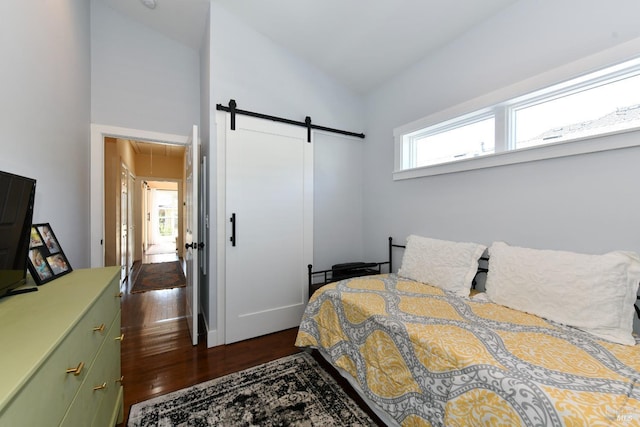 bedroom with lofted ceiling, a barn door, and dark wood-style flooring