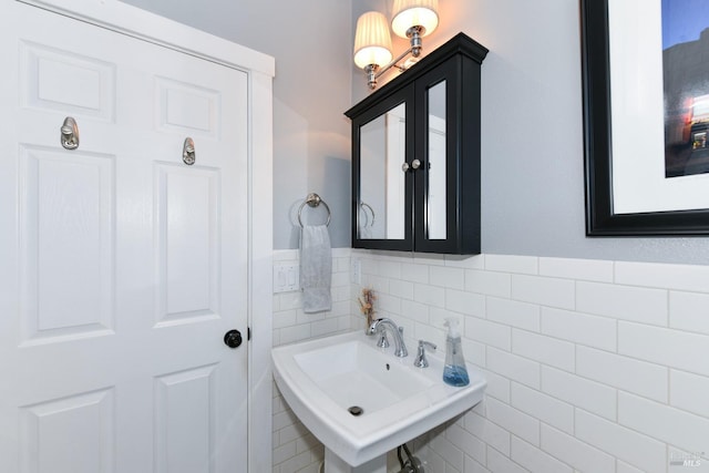 bathroom featuring wainscoting, a sink, and tile walls