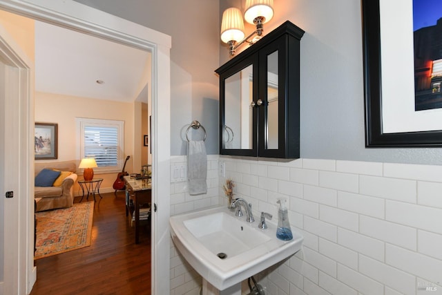 bathroom featuring wood finished floors, a sink, and tile walls