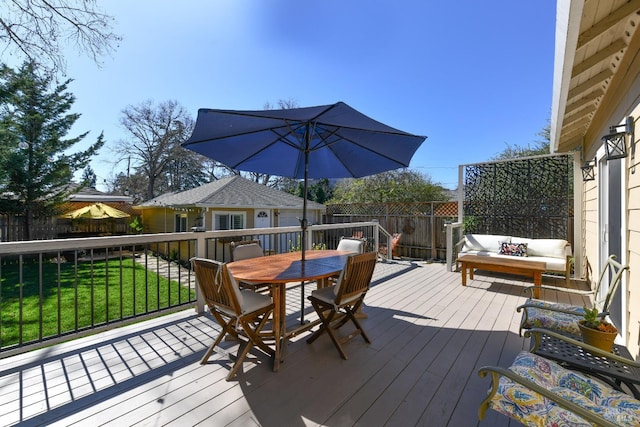 wooden terrace featuring outdoor dining space, fence, and a lawn