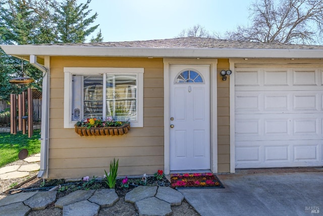 doorway to property with a garage, roof with shingles, and fence