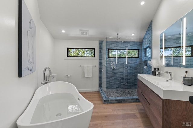 bathroom with visible vents, a stall shower, vanity, wood finished floors, and a freestanding tub