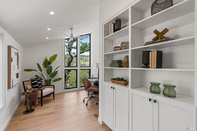 office space featuring light wood-style flooring, recessed lighting, a ceiling fan, baseboards, and expansive windows