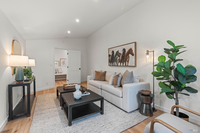 living room featuring lofted ceiling, recessed lighting, visible vents, baseboards, and light wood finished floors