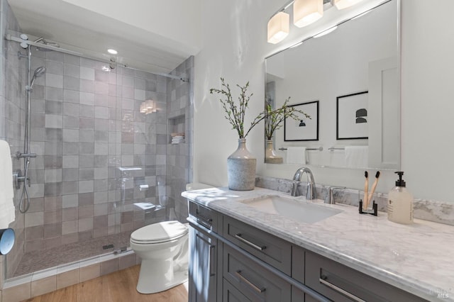 full bathroom featuring toilet, a shower stall, wood finished floors, and vanity