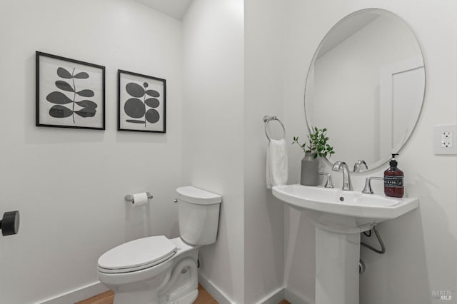 half bathroom featuring baseboards, toilet, and wood finished floors