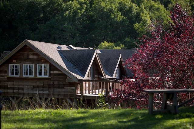 back of house featuring roof with shingles and a wooden deck