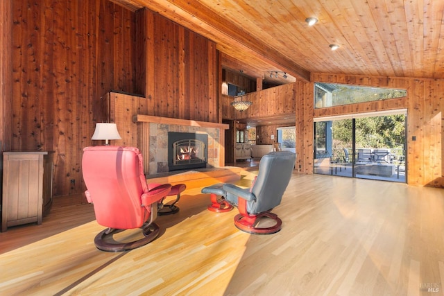 living area with wood ceiling, wooden walls, a tiled fireplace, and wood finished floors