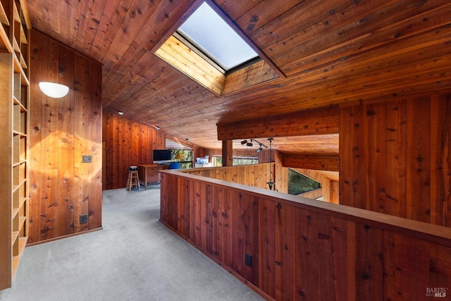 interior space with a skylight, wood ceiling, wooden walls, and carpet flooring