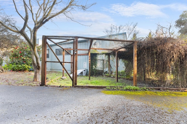 view of gate featuring an outbuilding and exterior structure