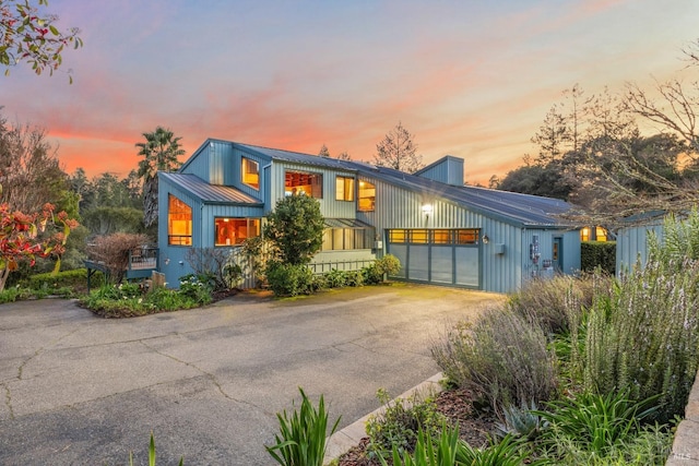 view of front of property featuring a garage, a standing seam roof, metal roof, and driveway